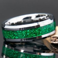 two wedding bands with green glitter inlays are shown on top of each other