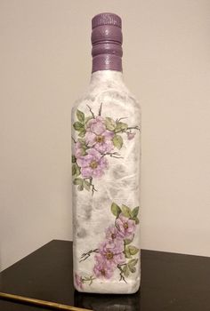 a bottle with flowers painted on it sitting on a table