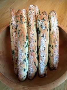 four breads in a wooden bowl on a table