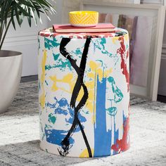 a colorful painted stool next to a potted plant