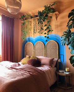 a bed sitting in a bedroom next to a window with plants hanging on the wall