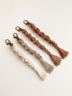 three tasseled keychains on a white background, one is brown and one is beige