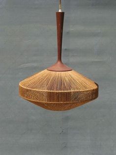 a hanging lamp made out of woven material with a wooden stick sticking out of it