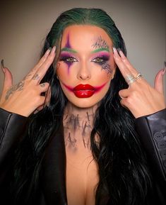 a woman with green hair and makeup has her hands on her head