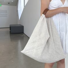 a woman in white dress holding a large bag