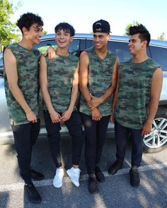 three young men standing next to each other in front of a car