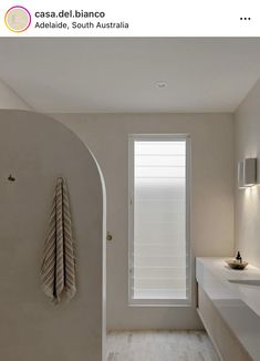 a white bathroom with an arched window and towel rack on the wall next to it