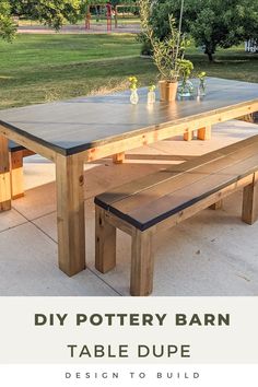 a wooden table with benches and potted plants on it in front of a grassy area