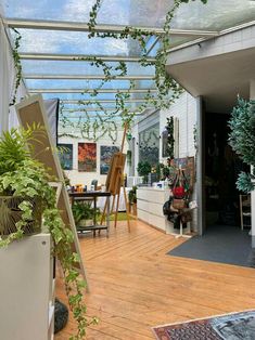 a room filled with lots of green plants and potted plants on top of wooden floors