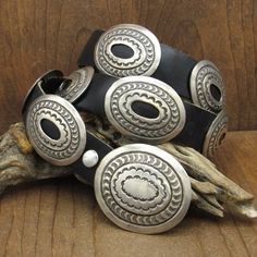 Southwest sterling silver concho belt on black leather. The buckle measures 2 1/4" long by 2" wide. The conchos are 1 15/16" long by 1 1/2" wide. The leather is 1" wide and the belt is 38.5" long from end to end. It weighs 268.7 grams in total weight. There are 2 copper strips on the back of each piece which allows you to slide the conchos to space them as you need or prefer. Each piece has ornate stamp work. There is a natural patina on the belt. It is in good condition. Thank you for looking. Formal Adjustable Concho Belt, Western Style Black Leather Jewelry, Hand Tooled Silver Leather Belt Buckles, Classic Hand Tooled Silver Belt Buckles, Classic Silver Belt Buckles, Silver Hand Tooled Adjustable Belt Buckles, Artisan Adjustable Concho Belts, Western Silver Belt Buckles With Concho, Black Leather Western Jewelry