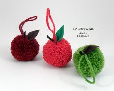 three crocheted apples with green and red tops, one has a leaf on it