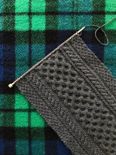 a green and blue plaid fabric with a zippered pouch on the side, next to a pair of scissors