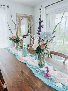 the table is set up with flowers and seashells for an ocean themed centerpiece