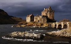 an old castle sitting on top of a rocky cliff next to the ocean under a cloudy sky