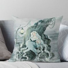 a mermaid sitting on top of a rock next to a giant fish throw pillow with an image of a woman and a monster in the background