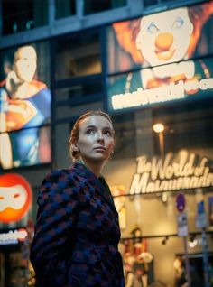 a woman standing in front of a building with many advertisements on the side of it