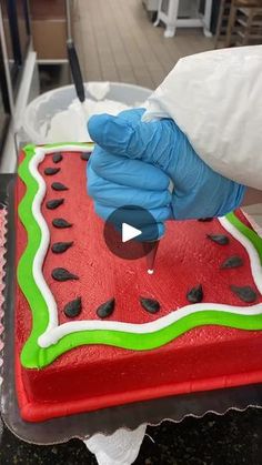 a person in blue gloves is decorating a watermelon cake