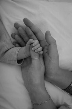 two people holding hands while laying in bed