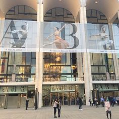 people are walking around in front of a building with banners on the side of it