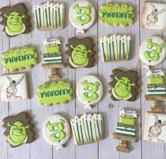 decorated cookies with green and white icing on top of a wooden table next to cupcakes