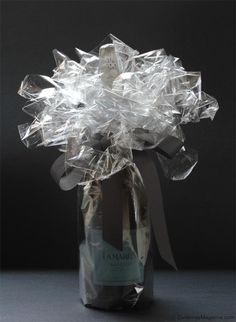 a glass vase filled with lots of clear plastic wrapped in silver foil and tied to a ribbon