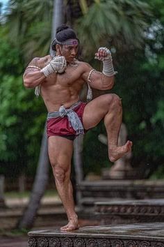 a man standing on one leg with his hands in the air while wearing red shorts