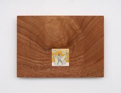 a square wooden object with a painting on it's side hanging on a wall