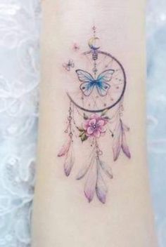 a woman's foot with a butterfly and dream catcher tattoo on it