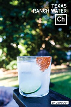 a glass filled with water sitting on top of a wooden table next to a tree