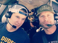 two men wearing headsets are sitting in an airplane