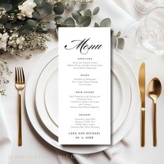 a table setting with white plates and silverware, gold cutlery, and greenery