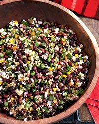 a wooden bowl filled with black beans and veggies next to a red napkin