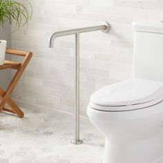 a white toilet sitting in a bathroom next to a wooden stand with a potted plant on it