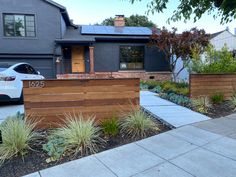 a car parked in front of a house next to a wooden fence and planter