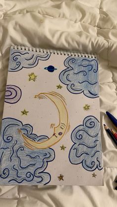 a notebook with an image of the moon and stars on it sitting on a bed