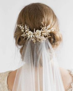 a woman wearing a veil with flowers on it's head and hair comb in front of her face