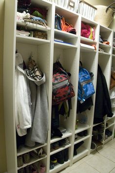 a white closet filled with lots of shoes and bags