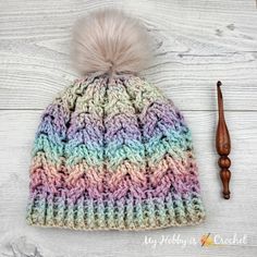 a multicolored knitted hat with a pom - pom on top