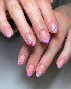 a woman's hands with pink and purple nail polishes on their nails,