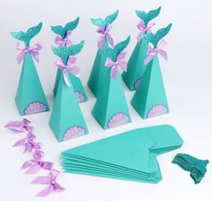 there are many paper cones and napkins on the table with ribbons around them that have little mermaid tails attached to them