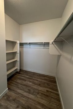 an empty closet with white walls and wooden floors