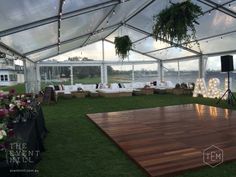 a party tent set up with couches, tables and flowers on the grass in front of it