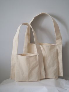 two canvas bags sitting side by side on a white surface, one is open and the other has an empty pocket