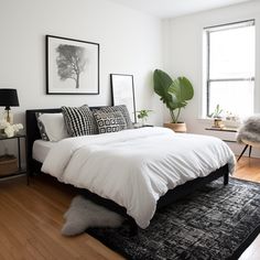 a bed with white sheets and black pillows in a bedroom next to a large window