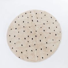 a round rug with small black dots on the top and bottom in cream colored wool