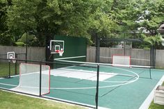 an outdoor basketball court in the middle of a yard with several hoops on it