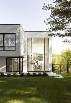 a modern house with large windows and grass