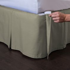 a person is holding onto a bed skirt