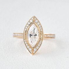 a rose gold engagement ring with a pear shaped diamond center and pave set diamonds around the band