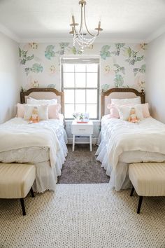 two twin beds in a bedroom with floral wallpaper and chandelier above them